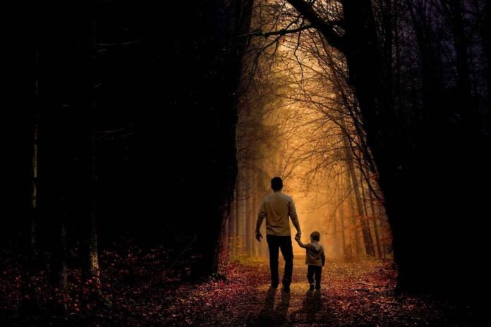 Kids Film Photography Tips : A father and son, holding hands, walk into a bright, golden-lit forest path. Represents the journey of teaching kids photography and film photography lessons.